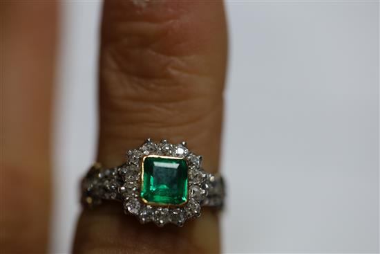 An antique 18ct gold, emerald and diamond cluster ring, the central square cut emerald (0.88ct) bordered by 14 old cut diamonds,